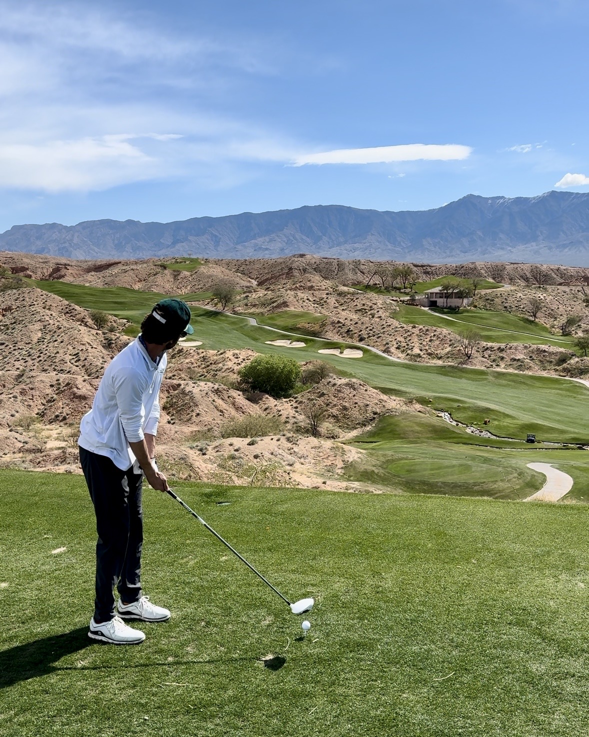 Justin golfing on a tee box with a mountain backdrop